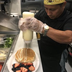 Man putting icing on a pancake