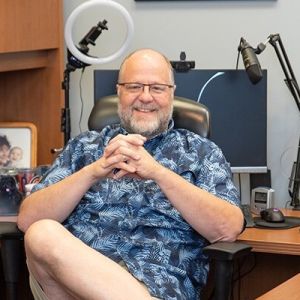 Older man sitting at his desk smiling