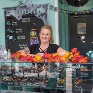 Lady standing behind a display counter filled with chocolate smiling at the camera