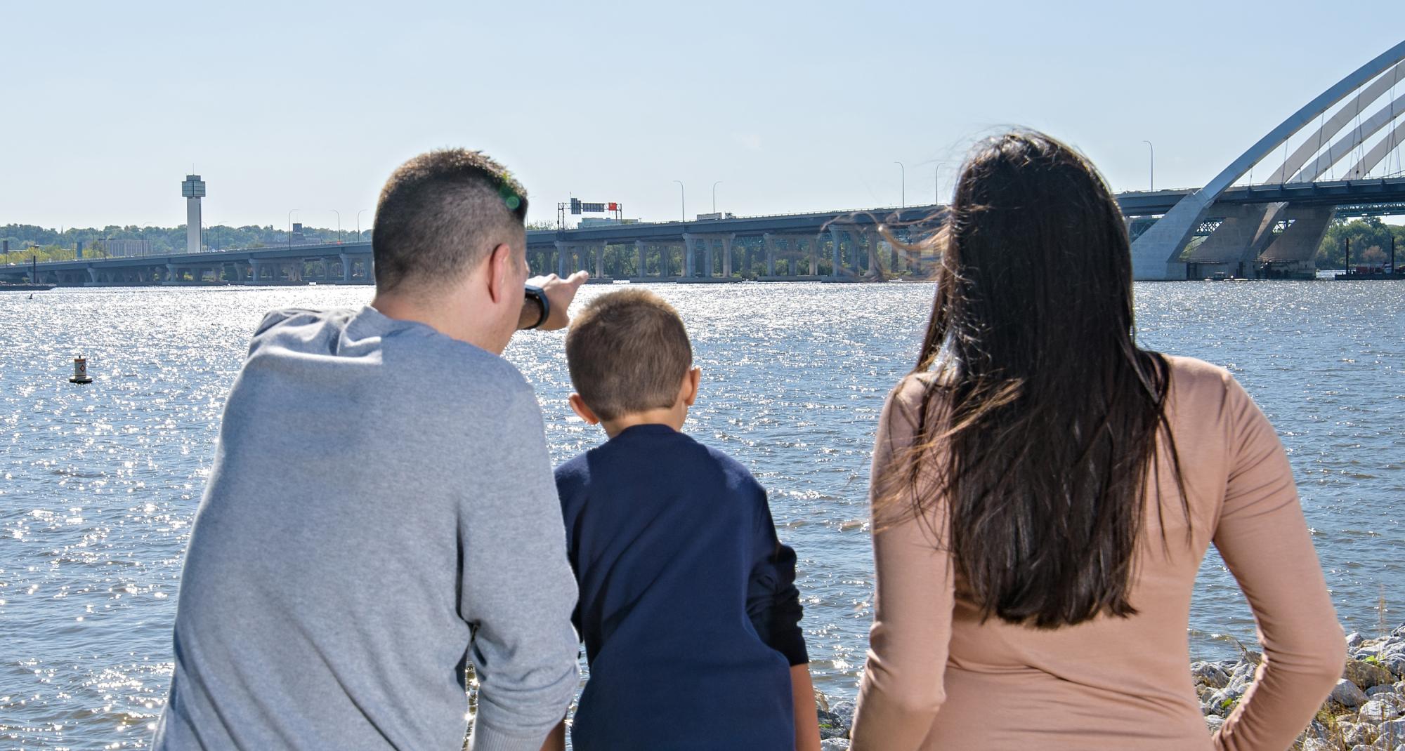 husband, wife, and small child looking out over to a bridge