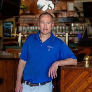 Man in a blue shirt leaning again a bar table