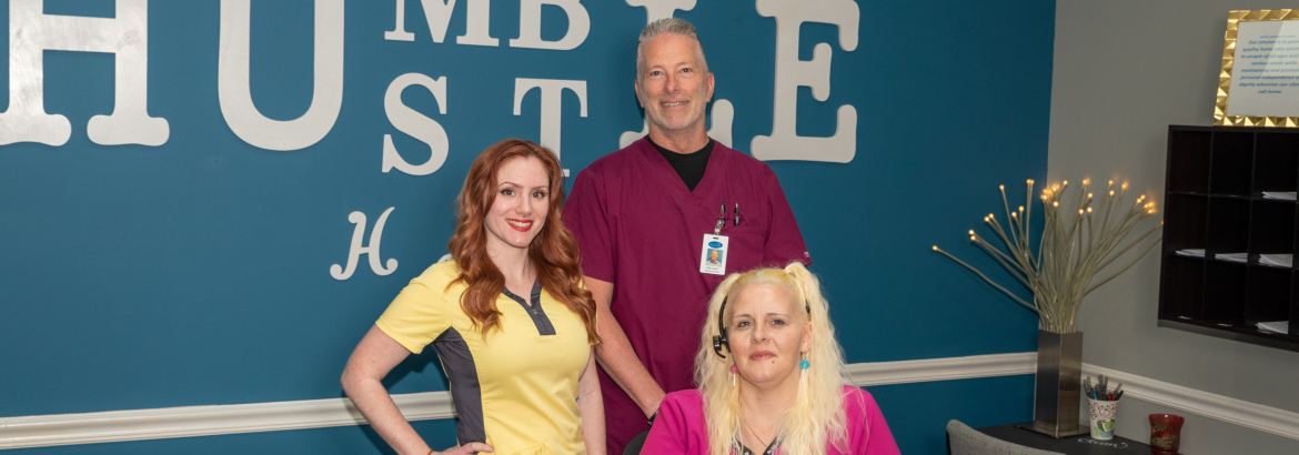 three people posing for a photo with a teal blue background