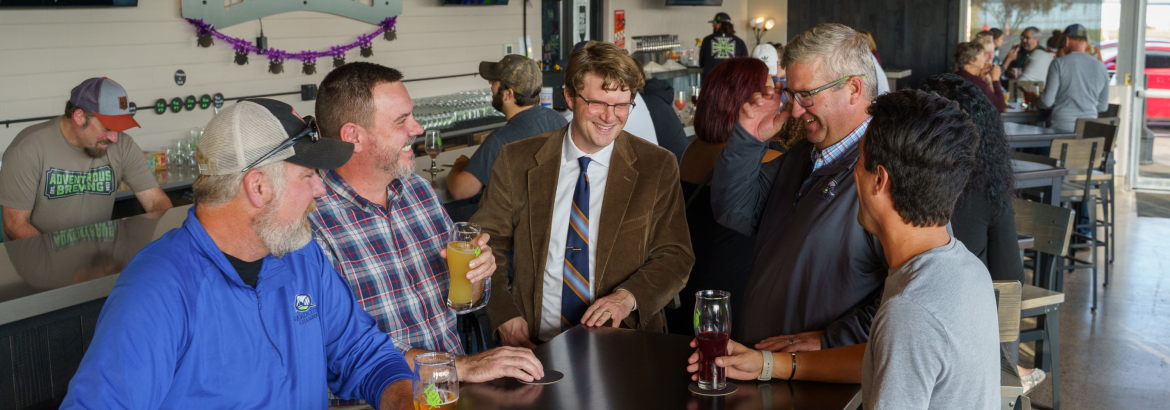 five men sitting down at a bar top drinking beer