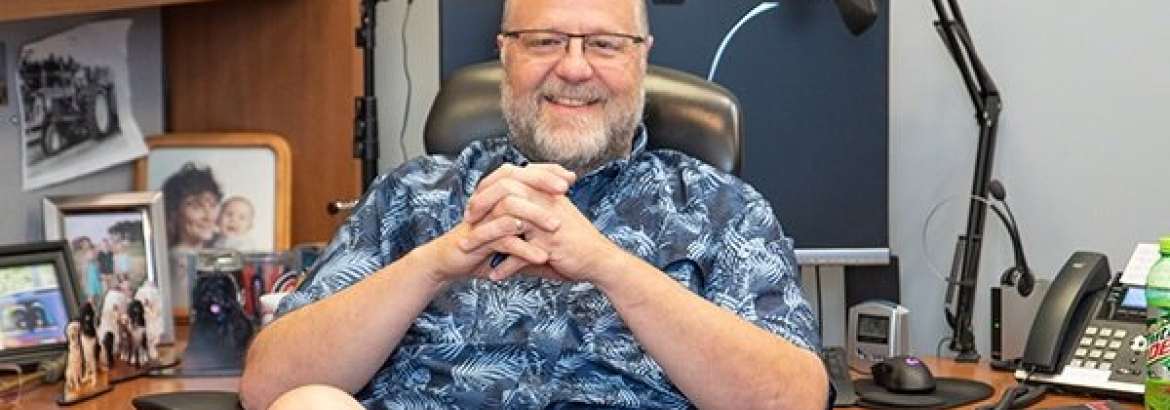 guy smiling at the camera at his office desk